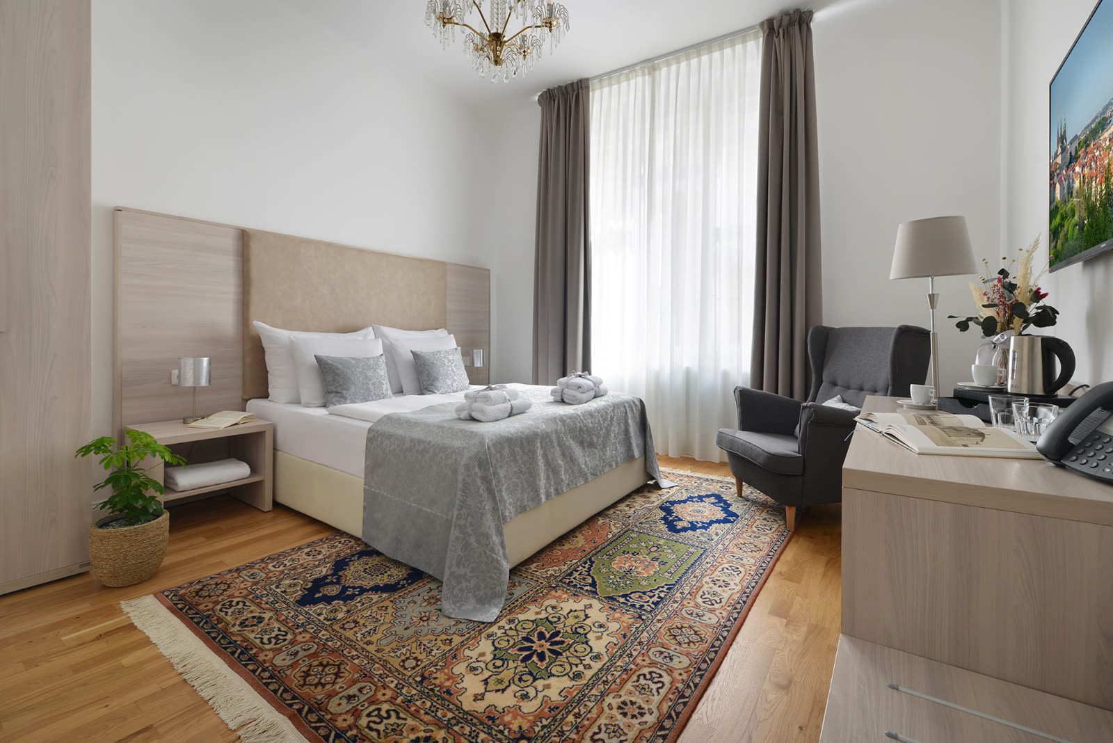 Bright double room with chandelier and Persian rug